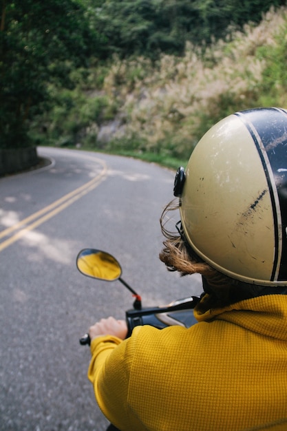 Foto vertical de uma pessoa com um capacete andando de moto