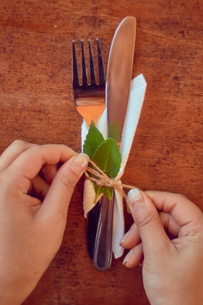 Foto vertical de uma pessoa fazendo utensílios de mesa para um casamento com enfeites