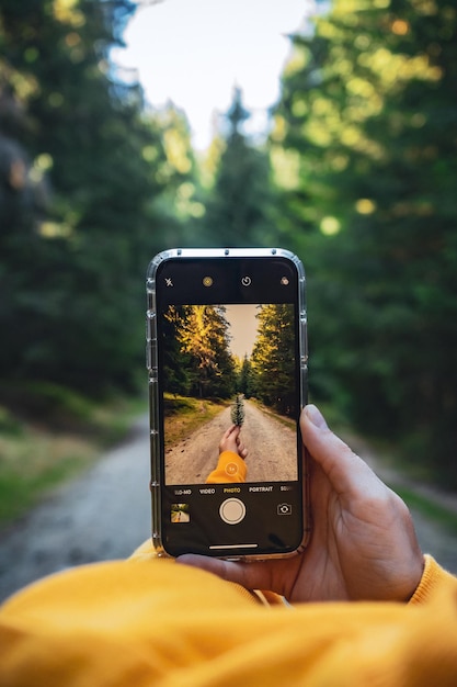 Foto vertical de uma pessoa tirando uma foto de uma folha com uma câmera de celular