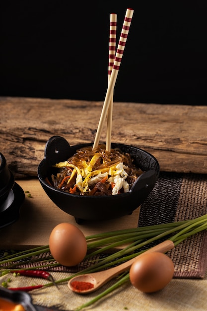 Foto vertical de uma tigela de comida deliciosa e pauzinhos em uma mesa de madeira