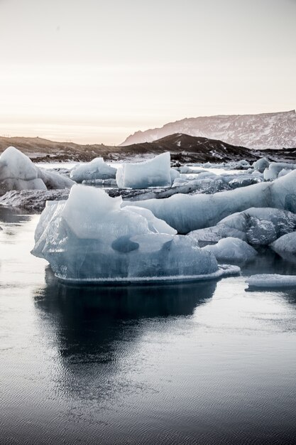 Foto vertical de vários pedaços de gelo na lagoa glacial Jokulsarlon, na Islândia
