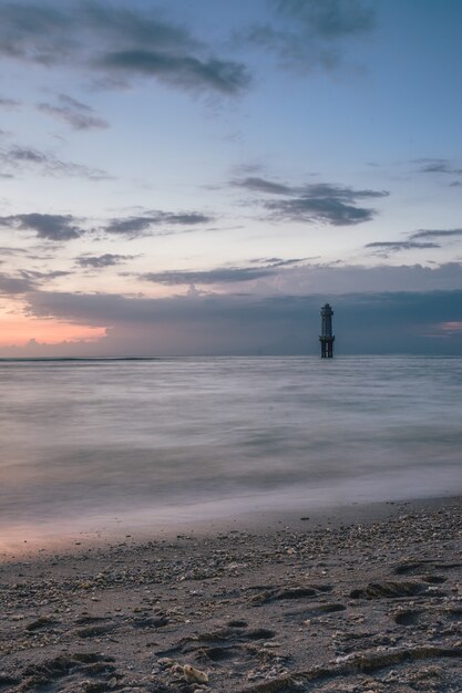 Foto vertical do farol no meio do mar