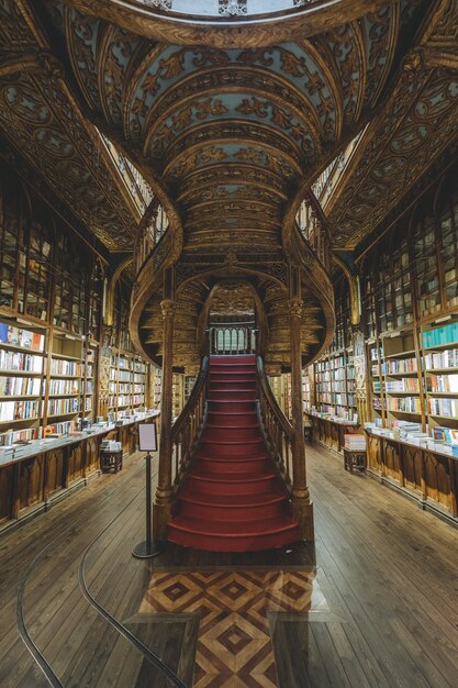 Foto vertical dos interiores da Livraria Centenária Lello capturada no Porto, Portugal