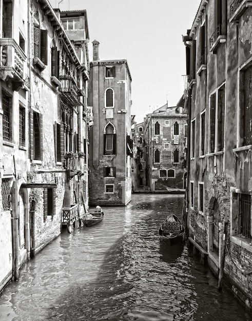 Foto vertical em tons de cinza de um canal no distrito histórico de Veneza, Itália