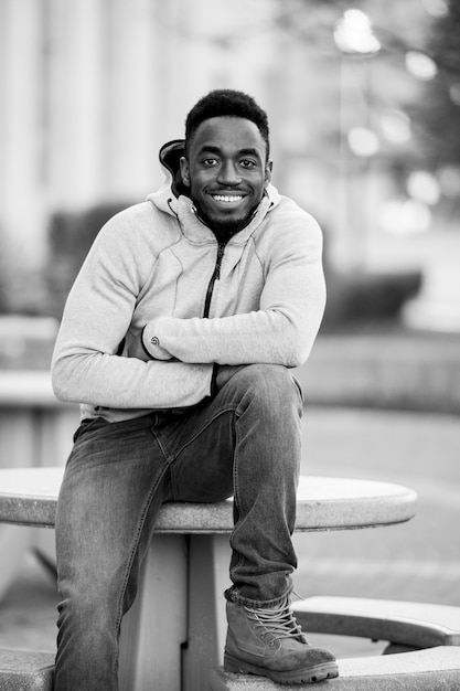 Foto vertical em tons de cinza de um homem afro-americano atraente sorrindo para a câmera