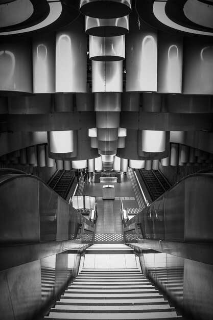 Foto vertical em tons de cinza de uma moderna estação de metrô com escadas rolantes em Bruxelas, Bélgica