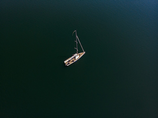 Fotografia aérea de drone de um barco à vela em um belo lago em um dia ensolarado