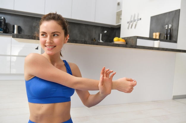 Fotografia em close de uma mulher fazendo exercícios em casa, esquentando, esticando as mãos, fazendo exercícios de fitness.