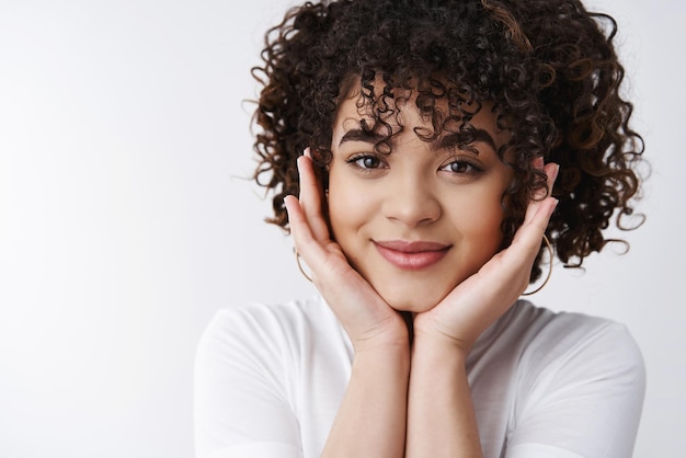 Foto grátis fotografia na cabeça glamour atraente morena penteado encaracolado sorrindo feliz tocando as bochechas sorrindo sedutor olhar câmera sentir amor sonhador suspirando assistindo drama romântico