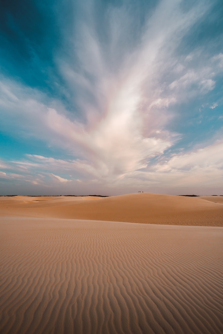Foto grátis fotografia vertical das colinas de areia sob as belas nuvens no céu