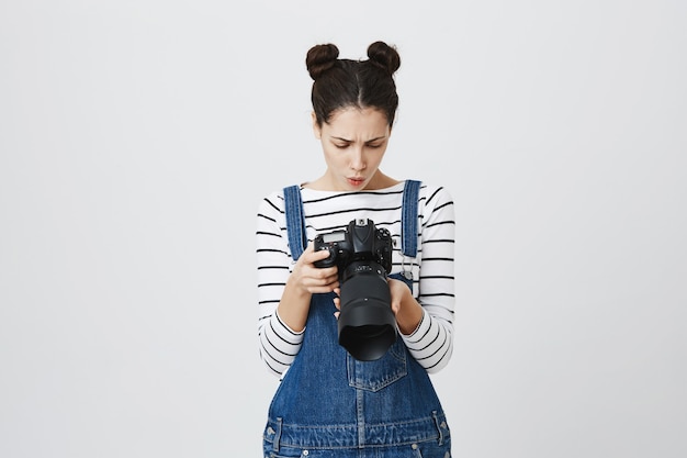 Fotógrafo de uma linda garota olhando para a tela da câmera em busca da imagem perfeita