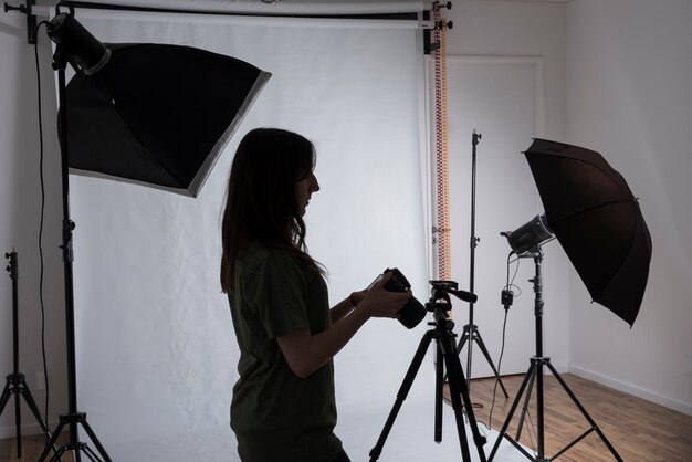 Fotógrafo fêmea no estúdio moderno da foto com equipamentos profissionais