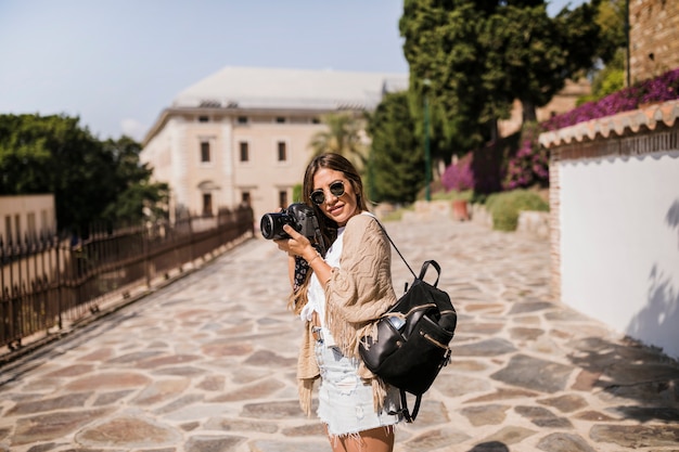 Foto grátis fotógrafo feminino com sua mochila em pé na rua