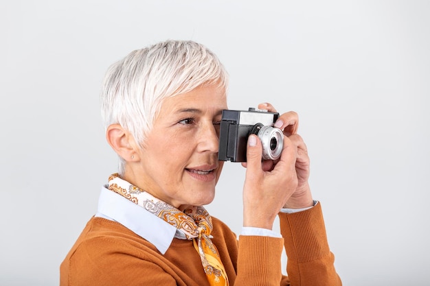 Fotógrafo feminino maduro tirando fotos com câmera retrô velha fotógrafo profissional fazendo uma sessão de fotos