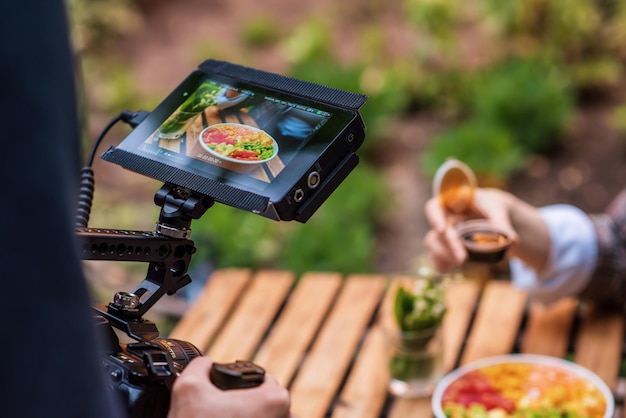 Foto grátis fotógrafo filmando uma poke bowl em uma câmera profissional em um parque