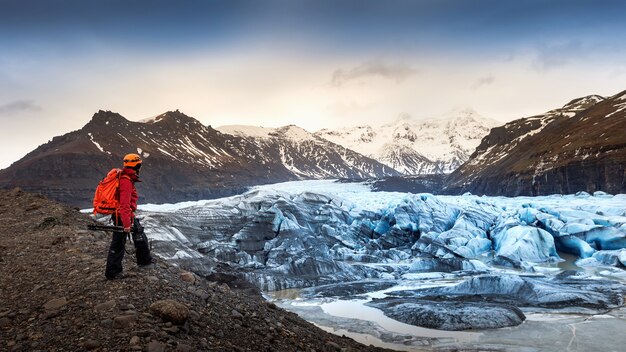 Fotógrafo profissional com câmera e tripé no inverno. fotógrafo profissional olhando para uma geleira na Islândia.