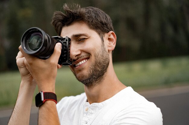 Fotógrafo profissional tirando foto. jovem com uma câmera. um homem tira uma foto com uma câmera profissional na natureza.