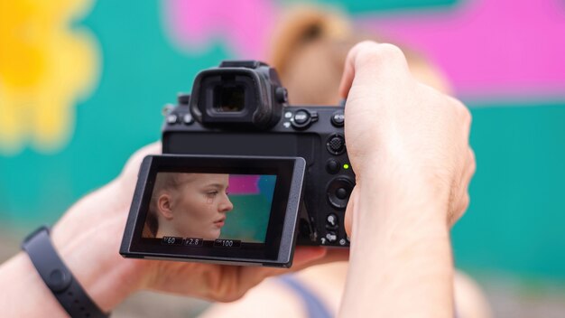 Fotógrafo tirando foto de uma jovem loira em roupas esportivas em treinamento ao ar livre, plano de fundo multicolorido