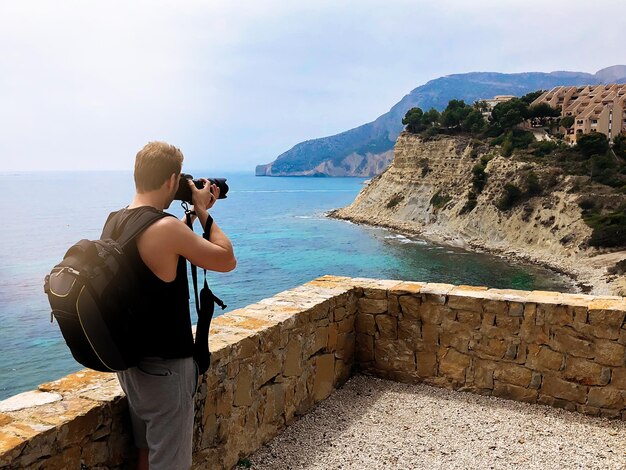 Fotógrafo tirando uma foto de uma costa do oceano