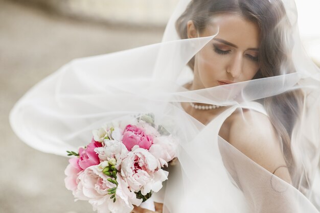 Fotos de noiva deslumbrante posando sob o véu do lado de fora