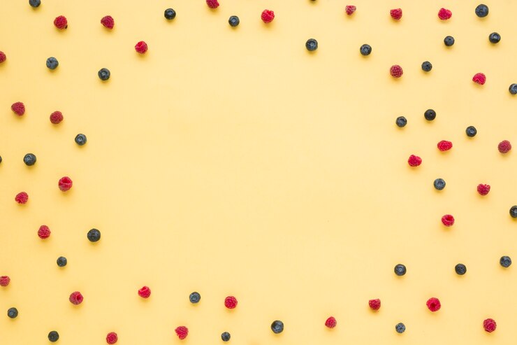 Foto grátis framboesas e mirtilos espalharam sobre fundo amarelo com espaço de cópia para escrever o texto