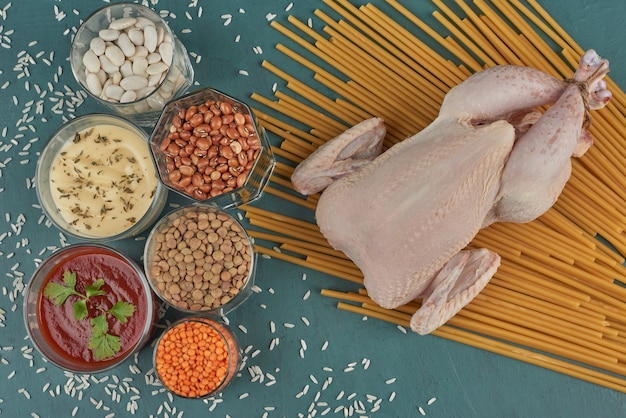 Foto grátis frango cru com macarrão, feijão e molhos.