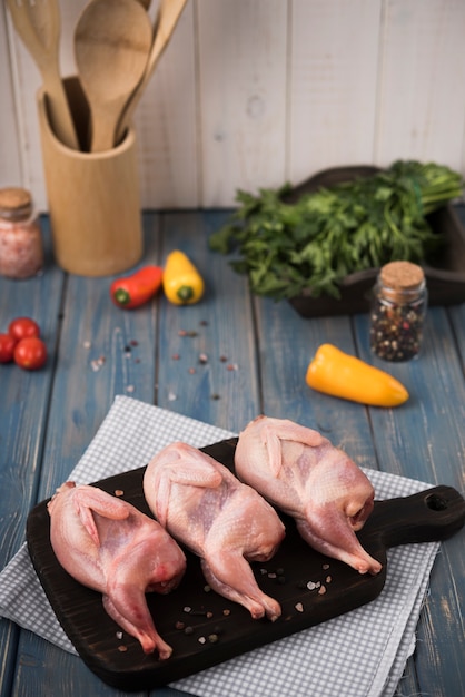 Frango cru de close-up na placa de madeira com pimentos