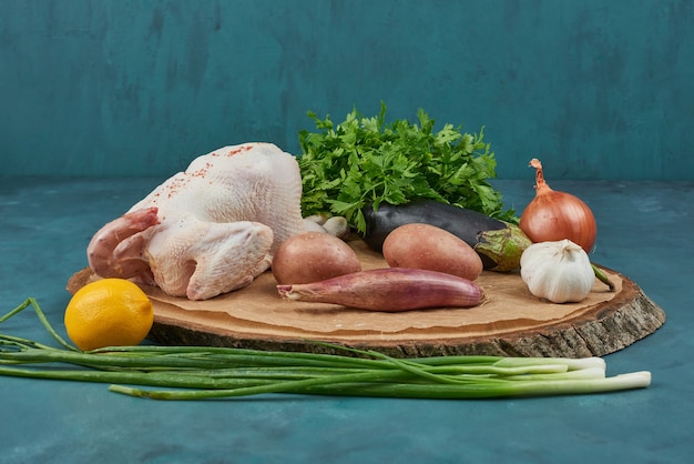 Frango em uma placa de madeira com legumes.