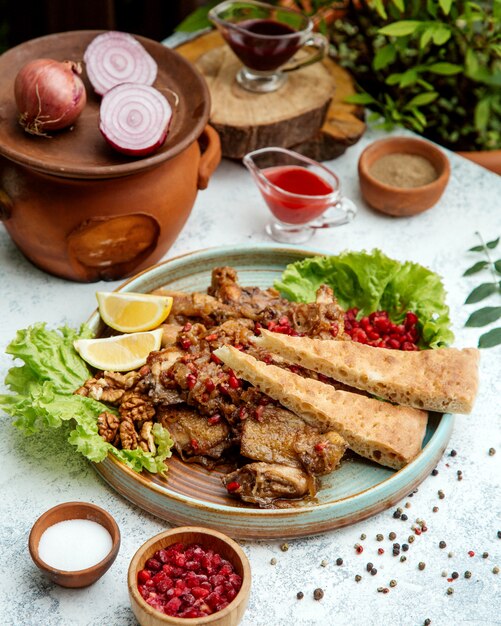 Frango frito com cebola e romã em uma panela de barro com pão