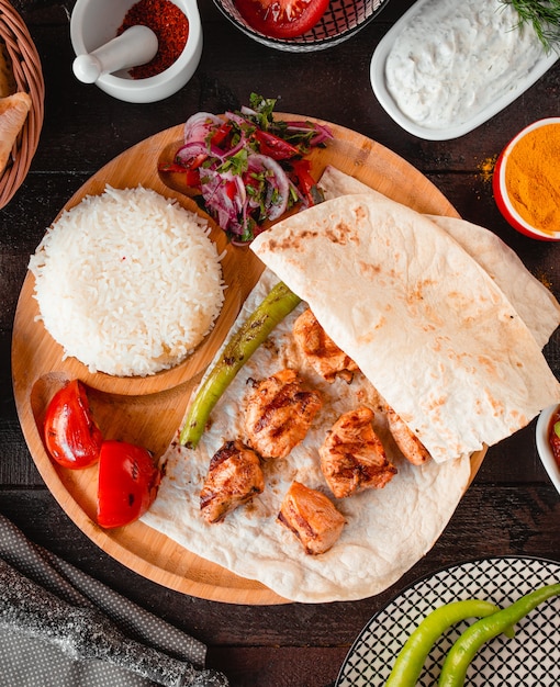 Frango frito com lavash e arroz em uma bandeja de madeira