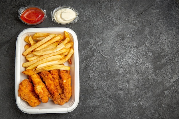 Frango frito crocante com batatas servido com maionese de ketchup na mesa escura