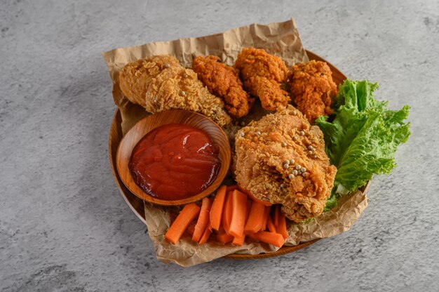 Frango frito crocante em um prato de madeira com molho de tomate e cenoura