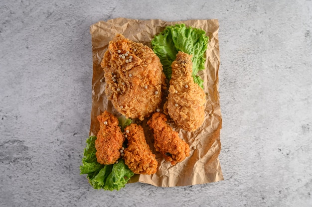 Frango frito crocante polvilhado com sementes de pimenta com salada em um papel marrom.