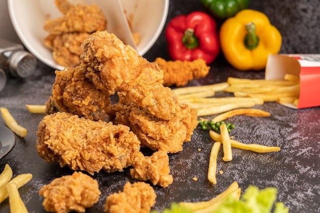 Frango frito e batatas fritas no chão de cimento preto.