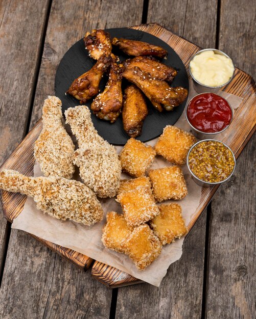 Frango frito em ângulo alto com nuggets e três molhos