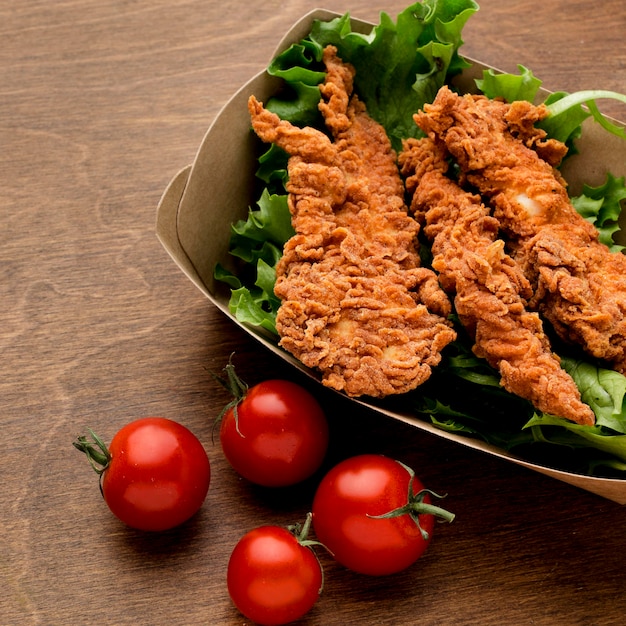 Frango frito em ângulo alto com salada e tomate