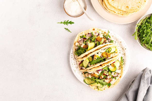 Foto grátis frango frito, rúcula, pepino, rabanete, cebola vermelha e molho de tortilha de trigo para o almoço, deliciosos burritos ou tacos mexicanos.