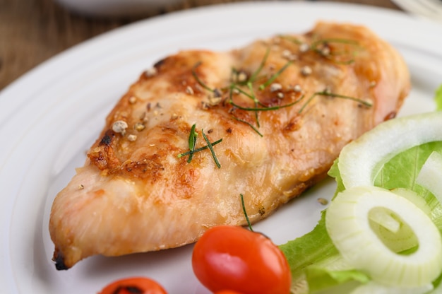 Foto grátis frango grelhado em um prato branco com tomate, salada e cebola.