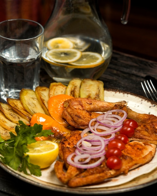 Frango grelhado servido com beringela, limão, salsa e