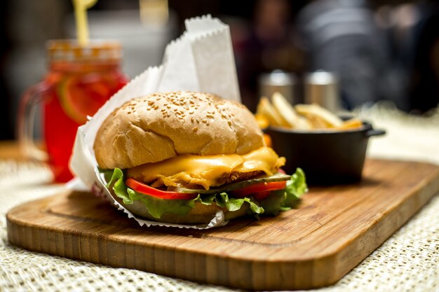 Frango hambúrguer ob placa de madeira alface queijo tomate pepino vista lateral