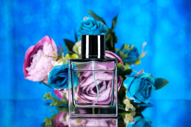 Frasco de perfume elegante com flores coloridas de frente para o fundo azul