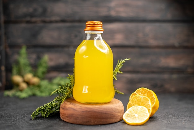 Foto grátis frasco de suco de laranja fresco de vista frontal em corte de placa de madeira