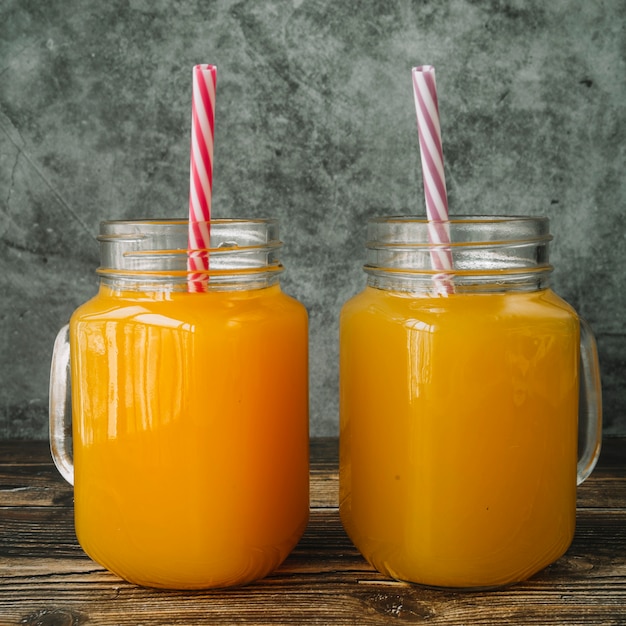 Foto grátis frascos com bebidas de laranja e palhas coloridas