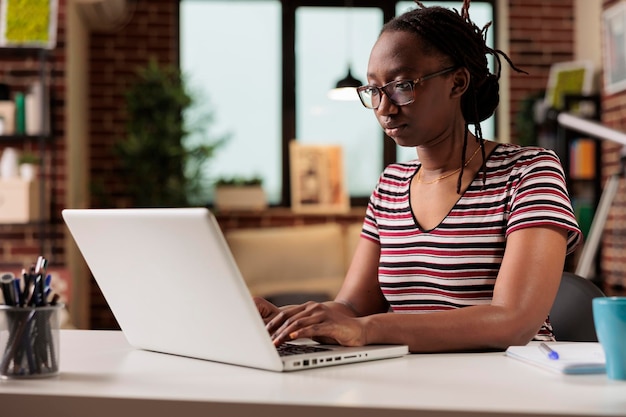 Freelancer trabalhando, digitando no teclado do laptop, pesquisando informações na internet em home office. Empregado escrevendo mensagem no computador, redação, sentado na mesa do local de trabalho