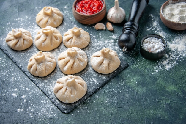 Frente bolinhos de massa crus com carne por dentro em uma superfície escura de cor de carne prato cozinha massa farinha cozinhando refeição