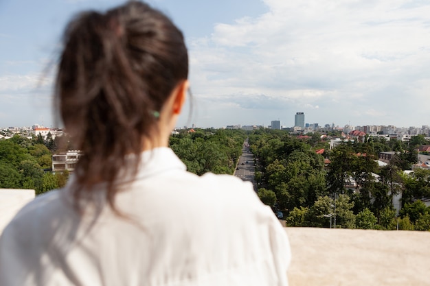 Frente de trás de uma mulher olhando a vista panorâmica da cidade metropolitana