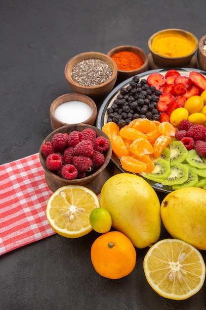 Foto grátis frente deliciosas frutas fatiadas dentro do prato com temperos na superfície escura frutas exóticas foto árvore madura vida saudável