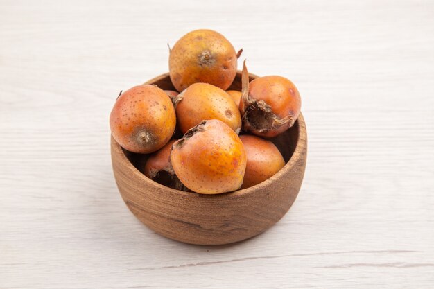 Frente frutas frescas marrons dentro do prato no fundo branco frutas dieta tropical madura cor exótica