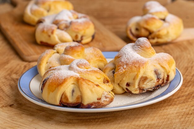 Frente mais de perto deliciosos pastéis com recheio dentro do prato na mesa de madeira, bolo de açúcar doce, assar massa de frutas