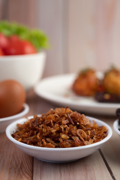 Fried Onion em um prato branco sobre um piso de madeira.